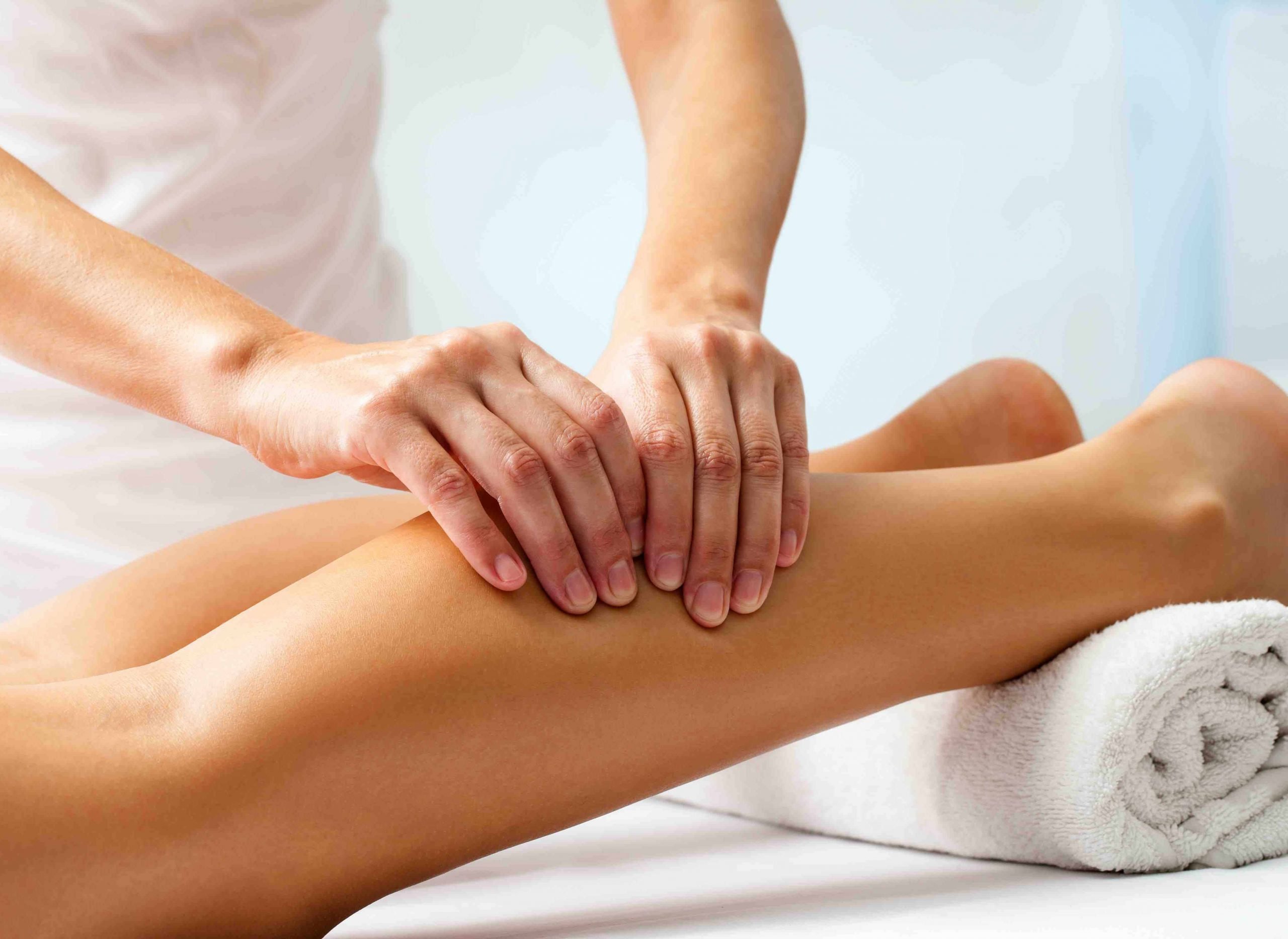 Detail of hands massaging human calf muscle.
