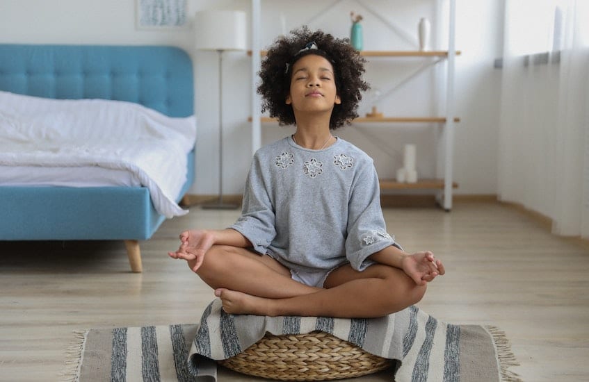 Young girl meditating. These 5 apps teach beginners how to meditate.